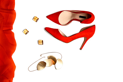 Top view to party outfit composition: red shoes, accessories, jewelry on white background, isolated. New Year and Christmas, Valentine's day party concept. Flat lay, copy space.