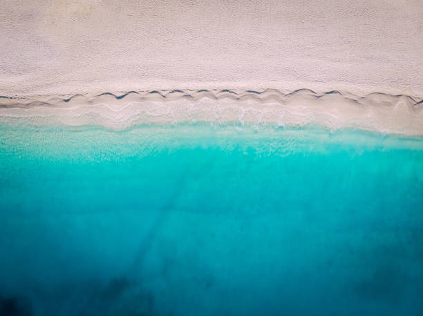 Top-down aerial view of a white sandy beach on the shores of a beautiful turquoise sea. stock photo