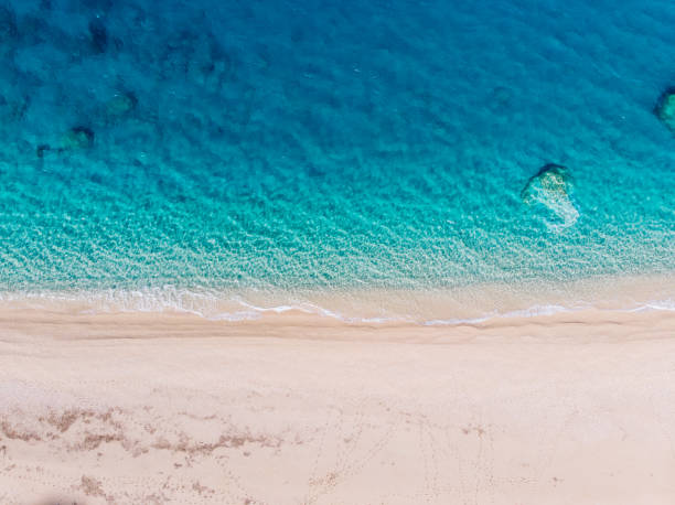 Top-down aerial view of a white sandy beach on the shores of a beautiful turquoise sea. stock photo