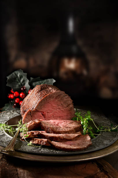 Topside Roast Beef II Succulent prime roast beef topside rump joint carved and ready for serving. Shot against a rustic, festive background with generous accommodation for copy space. beef stock pictures, royalty-free photos & images