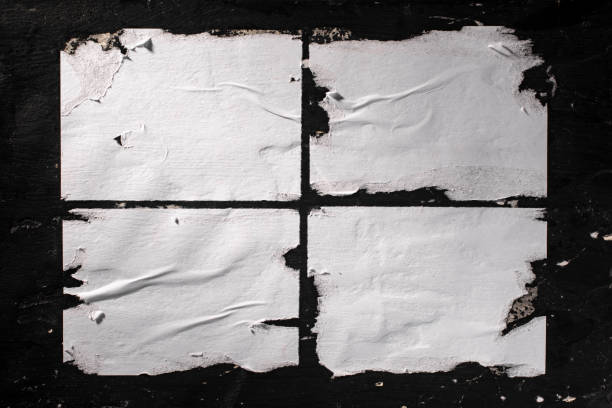 Torn sheets of white paper glued to the black wall. stock photo
