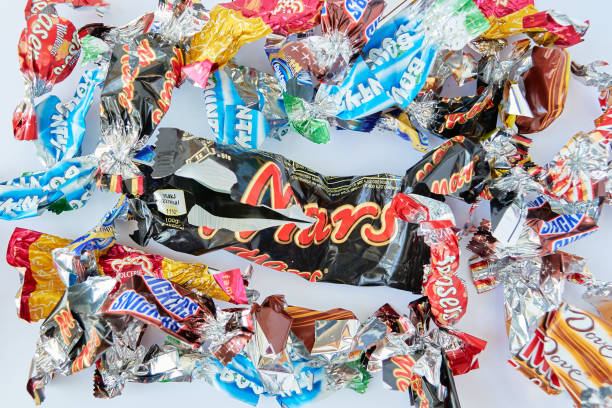 Torn wrappings of a mix of popular candy bars, in mini sizes, with a big Mars candy bar in the middle. stock photo