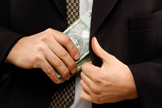 Torso closeup of man in suit pocketing a wad of money stock photo