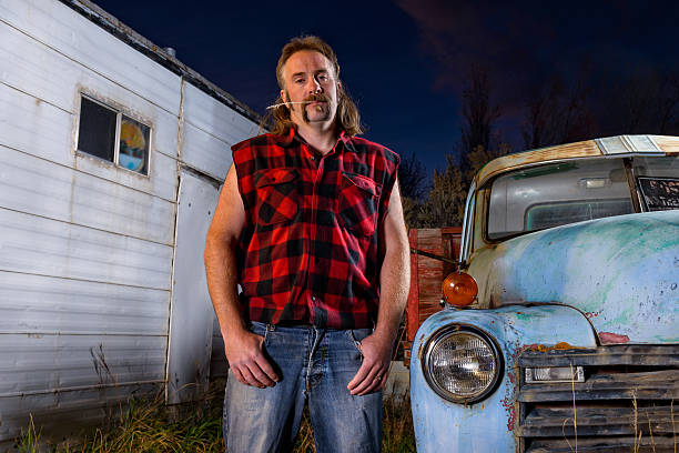 Tough Guy Redneck with Mullet Man looking angry with pickup truck.  Captured as a 14-bit Raw file. Edited in 16-bit ProPhoto RGB color space. mullet haircut photos stock pictures, royalty-free photos & images