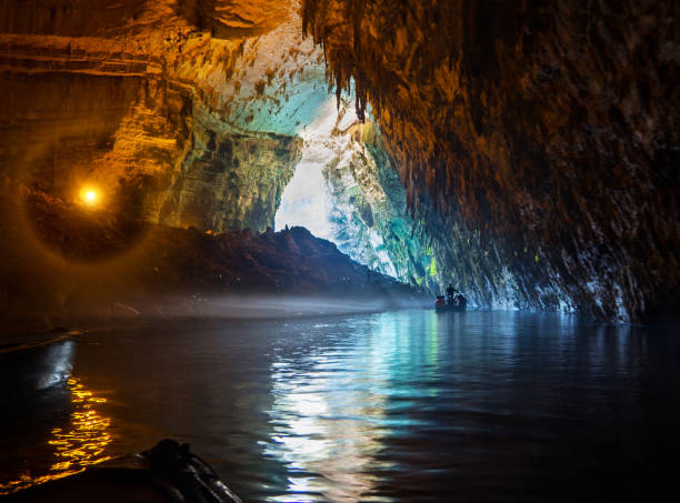 Tour by boat tourists in a cave with an underground lake Melissani on the island of Kefalonia, Greece Tour by boat tourists in a cave with an underground lake Melissani on the island of Kefalonia, Greece grotto cave stock pictures, royalty-free photos & images