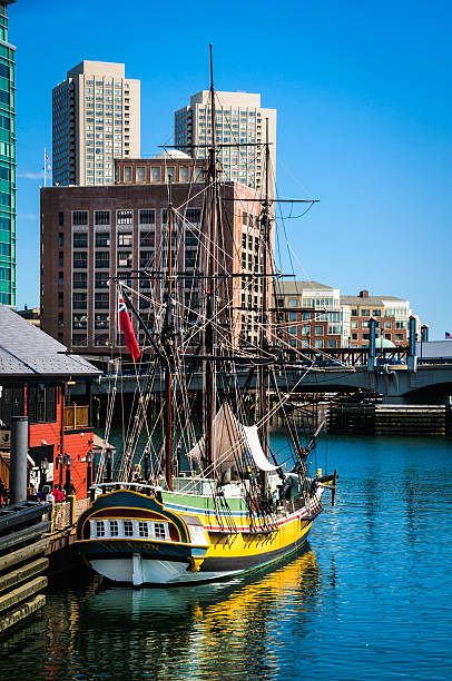 Touring the Eleanor Boston, Massachusetts, USA-August 12, 2013: A group of tourists walk along Griffin's Wharf as they prepare to tour the "Eleanor". The ship  is a replica of the original ship, which while docked here on December 16, 1773 was boarded by a group of men dressed as  Indians who tossed 114 crates of British East India Company tea  into the harbor in protest of the Tea Tax.  This has come to be known as the Boston Tea Party. boston tea party stock pictures, royalty-free photos & images