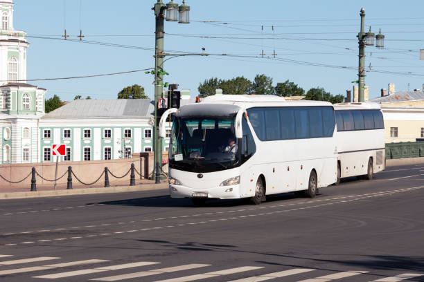 tourist bus going over the city bridge St. Petersburg, Russia - June 23, 2019: Modern white sightseeing bus on a city road in the early sunny morning. Transport to the Palace bridge unesco organised group stock pictures, royalty-free photos & images