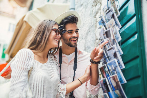 Tourist couple choosing postcard on the city Tourist couple enjoying sightseeing  exploring city and buy postcards souvenir stock pictures, royalty-free photos & images