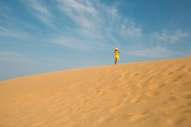 A tourist girl in a yellow dress runs along a sandy dune in the desert. Travel, sights of Dagestan, Sarykum dune A tourist girl in a yellow dress runs along a sandy dune in the desert. Travel, sights of Dagestan, Sarykum dune hot arabic girl stock pictures, royalty-free photos & images