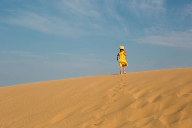 A tourist girl in a yellow dress runs along a sandy dune in the desert. Travel, sights of Dagestan, Sarykum dune A tourist girl in a yellow dress runs along a sandy dune in the desert. Travel, sights of Dagestan, Sarykum dune hot arabic girl stock pictures, royalty-free photos & images