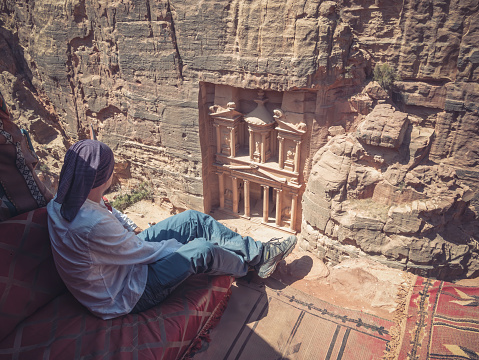 Tourist looking at the The Treasury (Al-Khazneh) from Al-Khubtha Trail Viewpoint in Petra, Jordan.