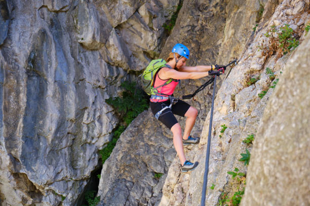 Tourist on via ferrata in Turda gorge (Cheile Turzii) Romania, crossing a traverse section, using straight arms and good climbing technique. stock photo
