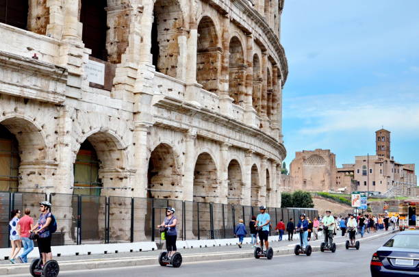 Tourist Rides Electric Scooter Segway on the street past the Coliseum in Rome stock photo