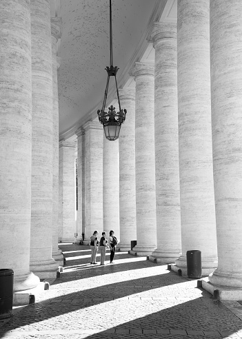 Rome, Italy, October 2017. Tourists enjoying a relaxing moment around the travertine pillars at the Saint Peter's basilica in Rome, Italy.