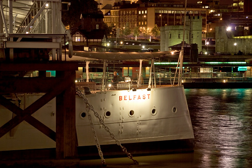Tourist Sitting On The Desk Of Hms Belfast Docked On The River