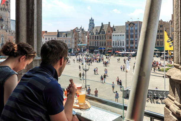 Tourists drinking beer and eating chocolate while enjoying the a panoramic view of the market square in the center of Bruges, Flanders. stock photo