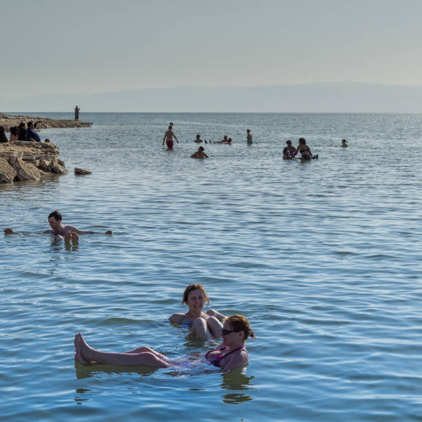 Tourists float in the Dead Sea and enjoy the warm salty water Dead Sea, Amman, Jordan, March 12, 2018: Tourists float in the Dead Sea and enjoy the warm salty water, middle east hot middle eastern girls stock pictures, royalty-free photos & images