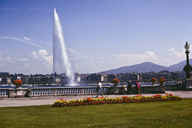 The Jet D'eau Fountain Geneva, Geneva Canton, Switzerland - July 29, 1978: Tourists look at the famous Jet D'eau fountain in Switzerland's Lake Geneva. jeff goulden switzerland stock pictures, royalty-free photos & images