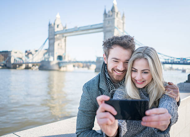 tourists taking a selfie in london with tower bridge - south bank london stockfoto's en -beelden