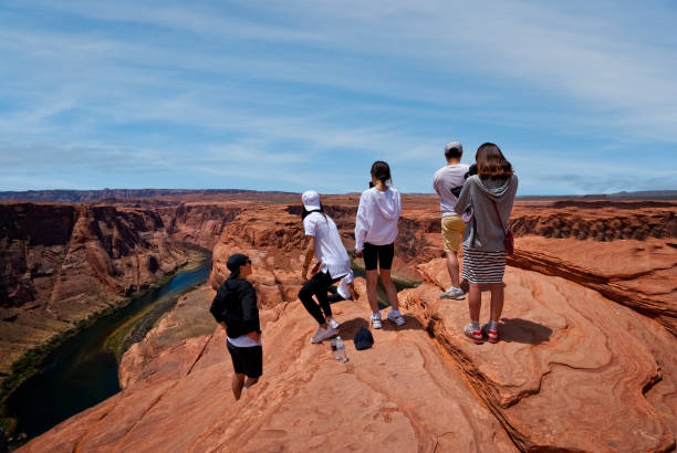 Tourists Taking Pictures at Horseshoe Bend Page, Arizona, USA - June 07, 2019: The Colorado River provides some incredible natural vistas along its length. One of the more unusual vistas is at Horseshoe Bend. The name was inspired by its unusual shape, a horseshoe-shaped meander of the river. Horseshoe Bend, located about four miles southwest of Page, Arizona, USA within the Glen Canyon National Recreation Area has become a very popular tourist attraction. In this picture, the tourists stand on the steep cliff overlooking the river. jeff goulden people stock pictures, royalty-free photos & images