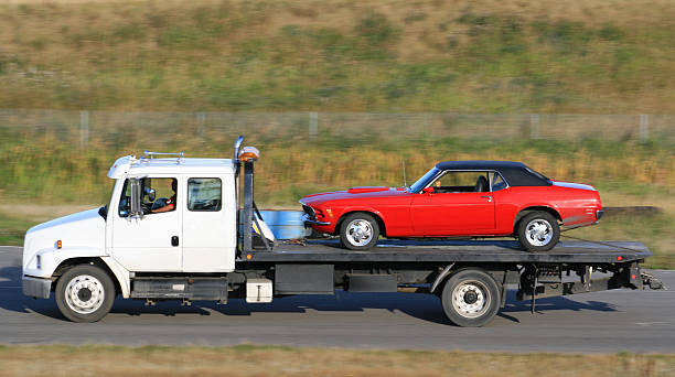 tow truck hauling a new red car - sleep stockfoto's en -beelden