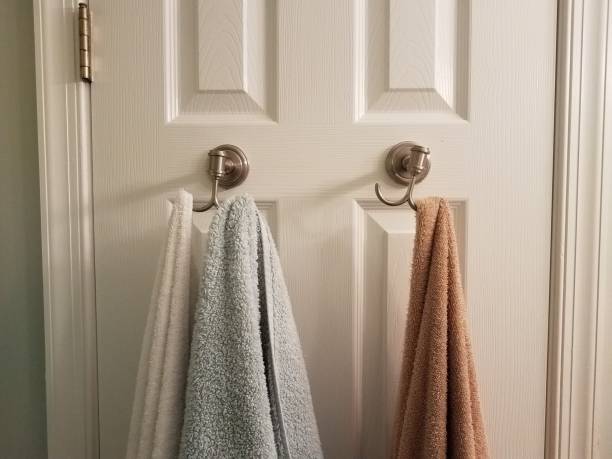 towels hanging on hooks on white bathroom door stock photo