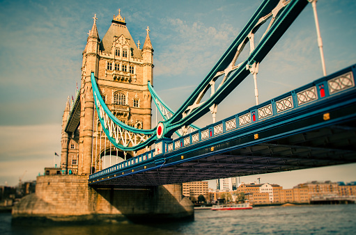 Tower Bridge in London,the capital city of United Kingdom, crossing Thames river.The view's perspective is from a low and close side, showing the structure underneath and, predominantly, one of the towers shaping the bridge at the background.