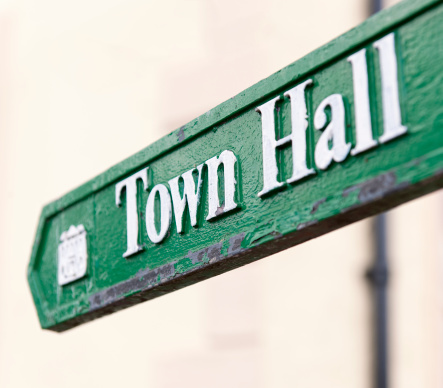 Close-up of a traditional, worn sign showing the direction to the town hall.