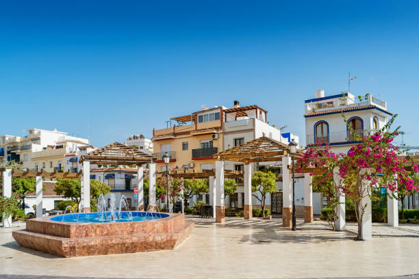 Town square in downtown Nerja Costa del Sol Andalusia Spain Stock photograph of a town square with fountain, pergola and blooming bougainvillea in downtown Nerja Andalusia Spain nerja stock pictures, royalty-free photos & images