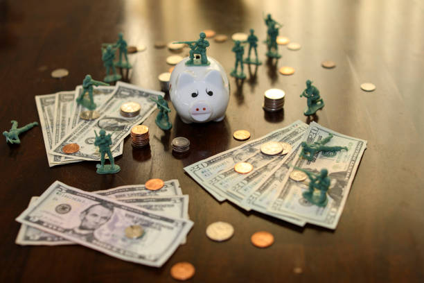 Toy soldiers guarding piggy bank and money concept stock photo