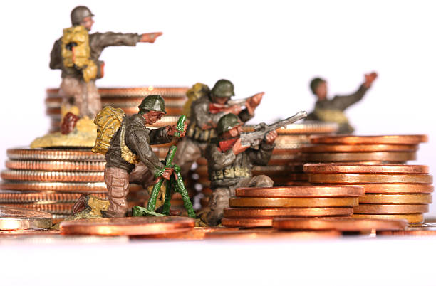 Toy soldiers posed on coin stacks depicting a money war stock photo