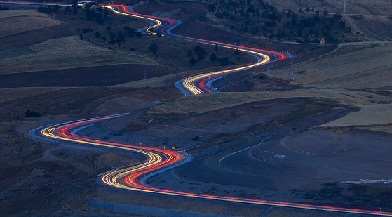 Headlight and tail light trails from passing traffic moving along a straight road.