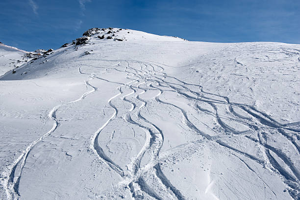Tracks running down in the snow on the mountain slopes stock photo