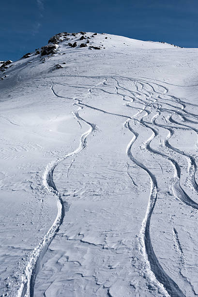 Tracks running down in the snow on the mountain slopes stock photo