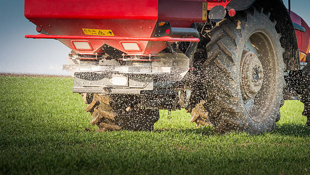 tractor fertilizing in field stock photo