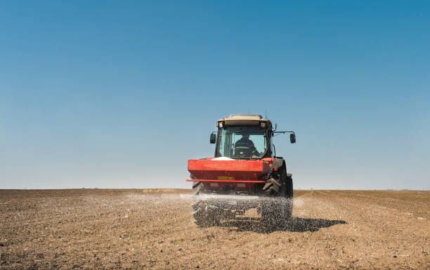 Tractor spreading artificial fertilizers  in field stock photo
