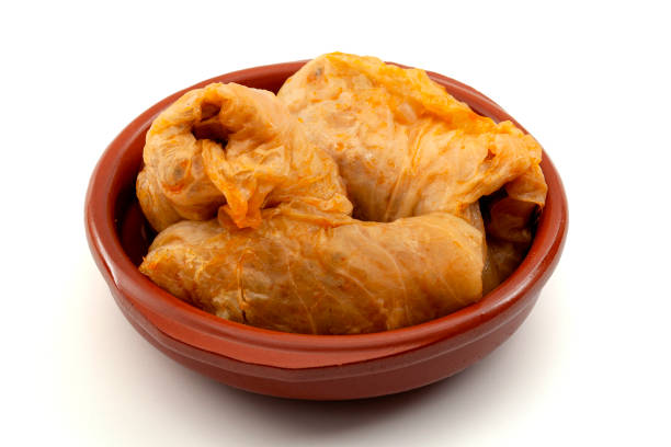 Traditional Balkan food recipe concept with cabbage rolls stuffed  with meat (Turkish:Sarma, Romanian: Sarmale) in brown pottery bowl isolated on white background with clipping path cutout stock photo