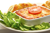 Close up image of traditional lasagne with salad and garlic bread on a white background