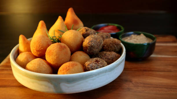 Traditional Brazilian snacks coxinha and quibe on wooden dark background. Selective focus. stock photo