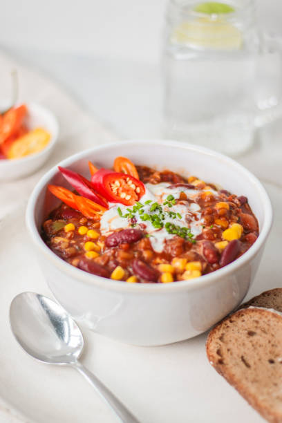 Traditional Chili Con Carne in Soup Bowl Traditional Chili Con Carne with sour cream topping in Soup Bowl at bright vibrant kitchen setting with food styling look casserole dish stock pictures, royalty-free photos & images