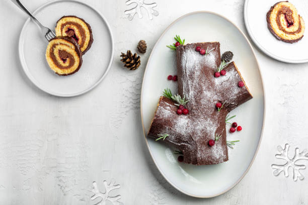 Traditional Christmas cake. Yule log or Buche de Noel. Sponge cake with chocolate cream, ganache, decorated with cranberries. Directly stock photo