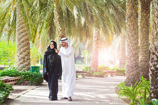Traditional Emirati young couple enjoying life outdoor Traditional Emirati young couple enjoying life outdoor. Shoot from Istockalypse Dubai 2015. abaya clothing stock pictures, royalty-free photos & images