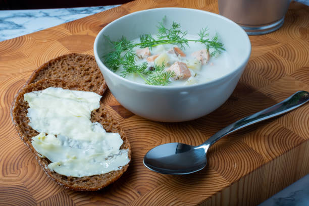 Traditional Finnish cuisine: Bowl of creamy salmon soup with dill topping. Two pieces of rye bread on the side. stock photo