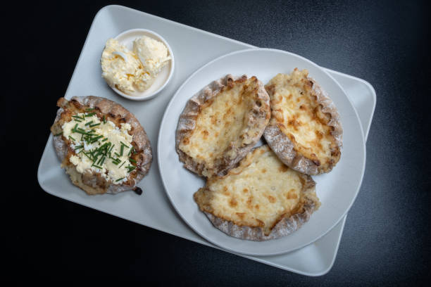 Traditional Finnish foods - Fresh Karelian pies with rice pudding filling and egg butter and chives topping against black background. stock photo