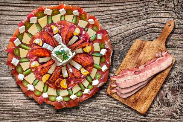 traditionella garneras förrätt välsmakande maträtt meze och stack av gourmet saftiga bacon skivor på skärbräda serveras på rustik furu trä picknickbord - pork pine bildbanksfoton och bilder
