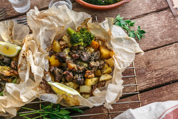 Traditional Greek kleftiko, an oven-baked lamb stew with potato, olive oil, onion, carrot, garlic and herbs, served with lemon and ouzo. stock photo