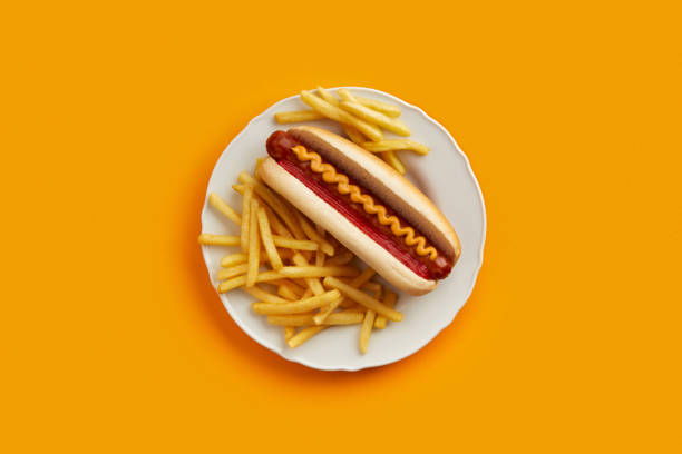 Traditional hot dog with french fries in plate on orange background. Restaurant menu stock photo