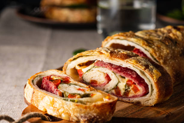 Traditional Italian Stromboli stuffed with cheese, salami, red pepper and spinach. Photo in a dark style. stock photo