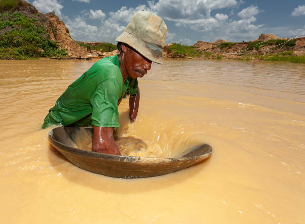 A traditional miner is shaking his panning tray on bright noon at traditional diamond panning at Cempaka, Banjarbaru, South Borneo Indonesia. stock photo