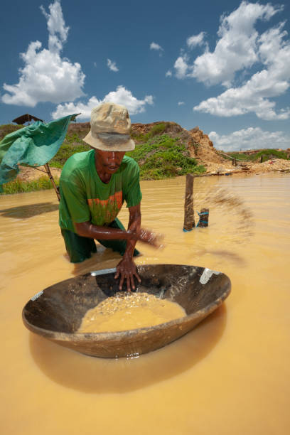 A traditional miner is sorting out rocks from his panning tray bright noon at traditional diamond mining at Cempaka, Banjarbaru, South Borneo Indonesia stock photo